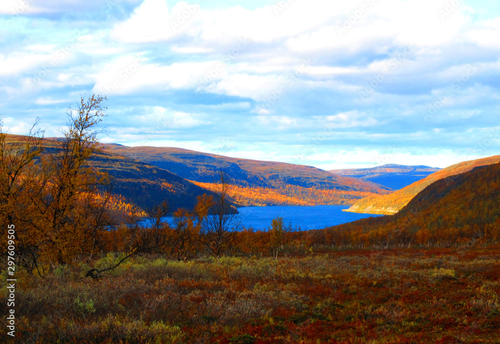 Mountain landscape in Northern Norway. Autumn colors, mountain lake, colorful cloudy sky. Awesome fall season.