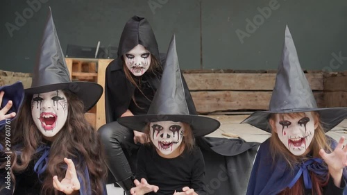 Four little girls dressed as witches, zombies, skeleton and make-up look intimidating at the camera. Slow motion photo