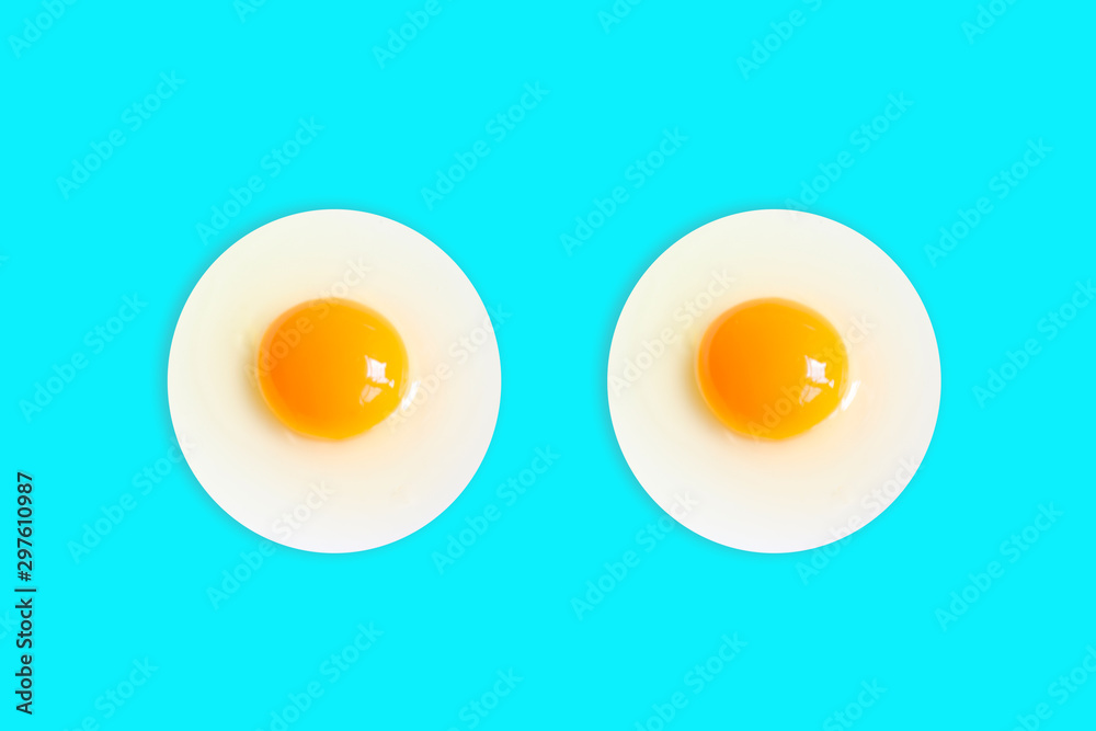 Two Organic round (White eggs and yolk )of chicken Cooked high protein good for health decorative isolated on pastel light blue food background texture close-up Two Organic round (White eggs and yolk )of chicken Cooked high protein good for health decorative isolated on pastel light blue food background texture close-up