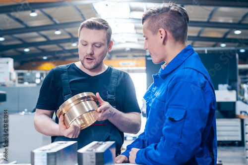 Master discussing a workpiece with his apprentice or trainee photo