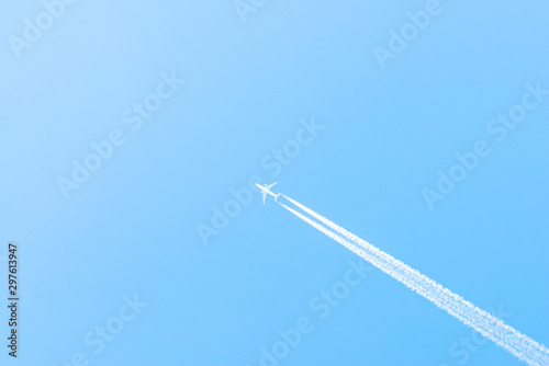 Airplane in a blue sky with clouds and condensation trails, Germany