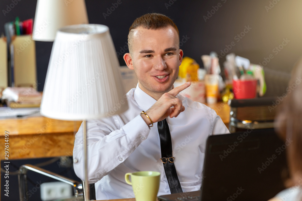 portrait of a cheerful businessman working in an office. a man sits at his Desk. the man gestures and smiles portrait of a cheerful businessman working in an office. a man sits at his Desk. the man gestures and smiles