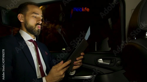 Businessman during a business video call in the back seat of his luxury car photo