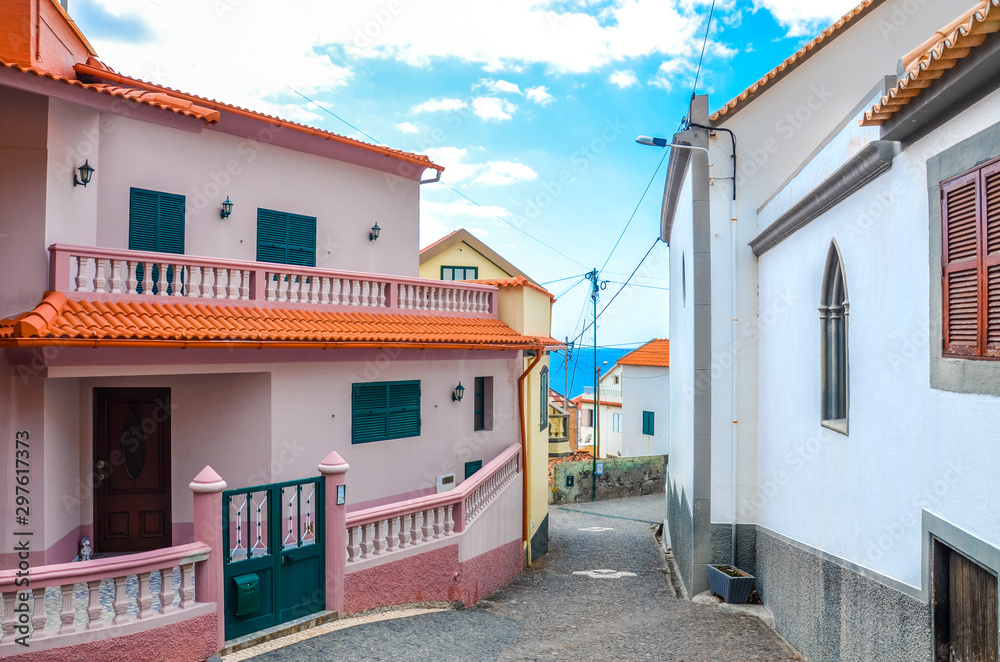 Buildings in coastal village Jardim do Mar, Madeira, Portugal. Waters of the Atlantic ocean in the background. Narrow street. Tourist destination. Pink facade