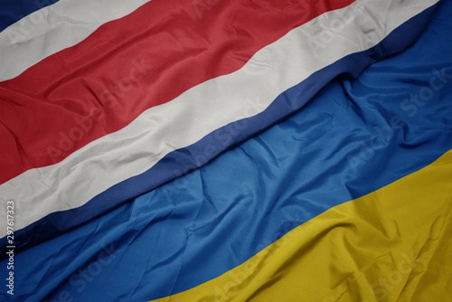 waving colorful flag of ukraine and national flag of costa rica.