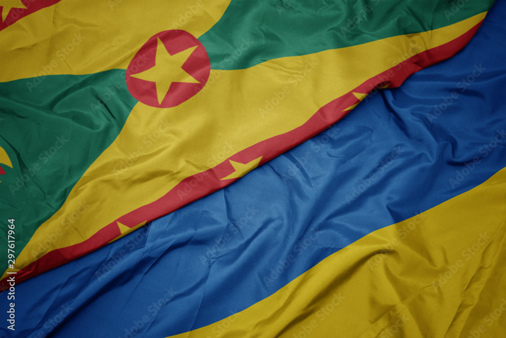 Obraz premium waving colorful flag of ukraine and national flag of grenada.