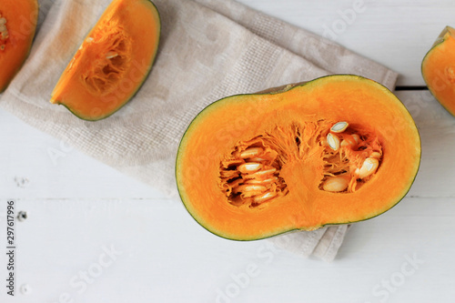 Group of halves and whole pumpkin on a light wooden background. Pumpkin is not cleared of seeds. photo