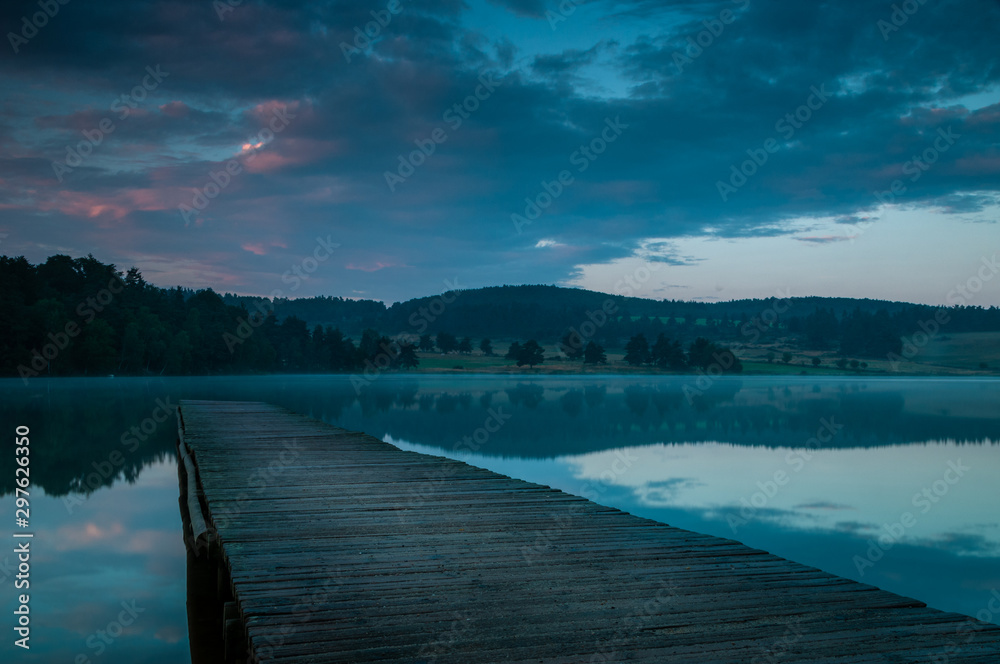 Naklejka premium wooden jetty on lake at sunrise.