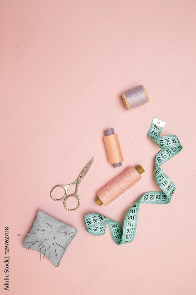 Top view of sewing machine with accessories for sewing, scissors and a measuring tape on pink background - obrazy, fototapety, plakaty 