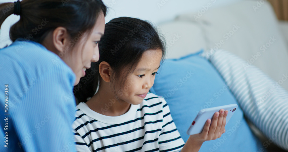 Mother and daughter look at the mobile phone together at home Mother and daughter look at the mobile phone together at home