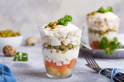 Layered Olivier salad with boiled vegetables in portion jar. Traditional Russian cuisine. 