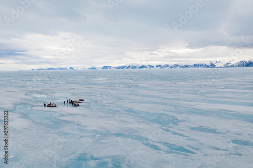 Aerial drone photo of tourists travelling by Qamutiik on the sea ice near Sirmilik National Park in Nunavut, Canada © Colin
