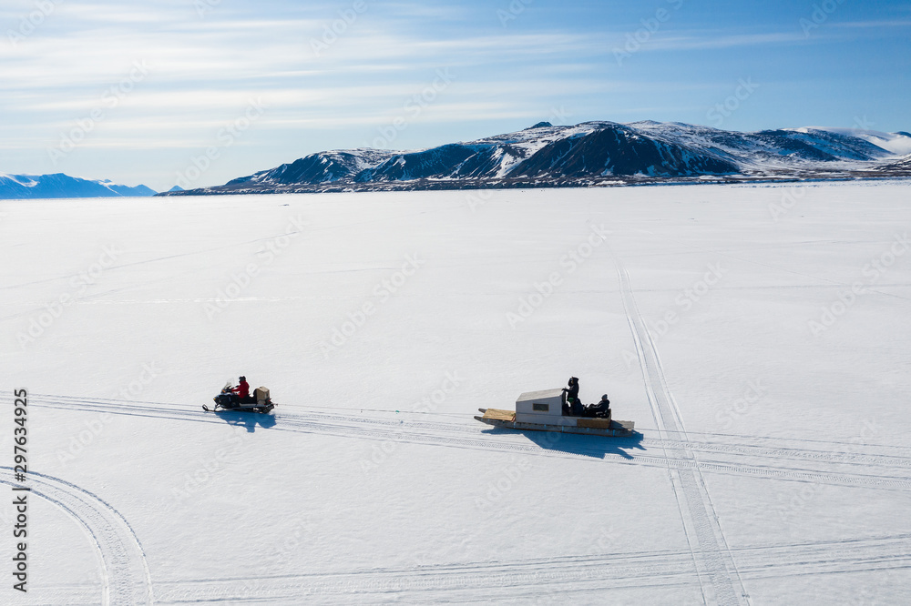 Aerial drone photo of tourists travelling by Qamutiik on the sea ice near Sirmilik National Park in Nunavut, Canada