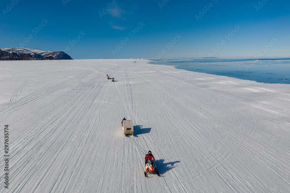 Aerial drone photo of tourists travelling by Qamutiik on the sea ice near Sirmilik National Park in Nunavut, Canada