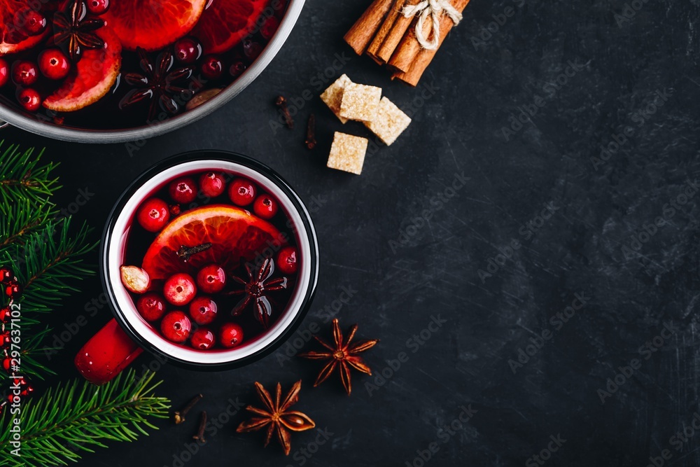 Mulled Wine Hot Drink with Cranberries, oranges, apples and spices on dark concrete background.