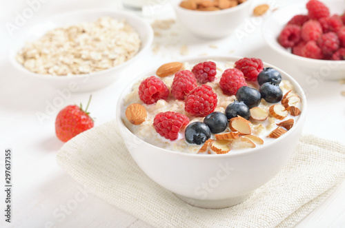 Tasty oatmeal porridge with raspberries, blueberries and nuts in bowl