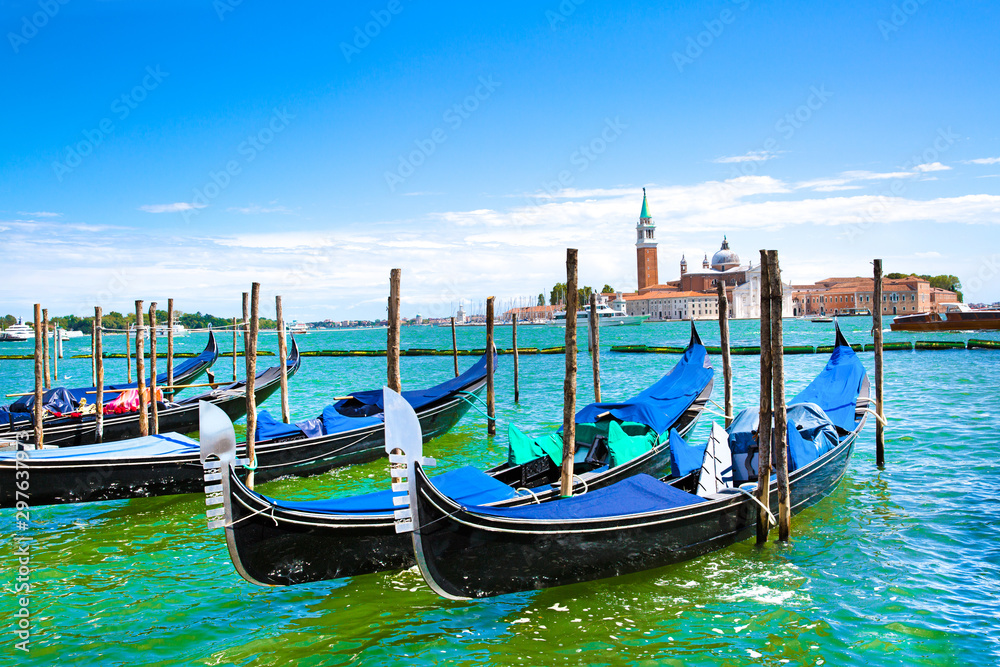 Gondolas and bright turquoise water of canal. Grand Canal in Venice, Italy. Sunny summer vacations. Beautiful landscape with bright colors. 