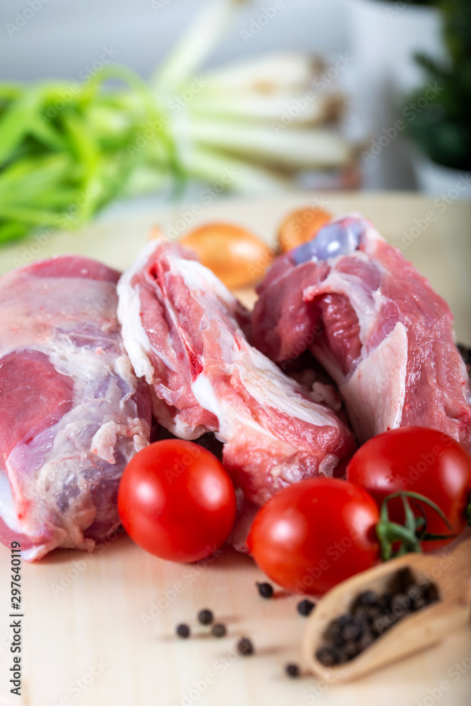 Raw meat slices on chopping board with fresh vegetables and spices Raw meat slices on chopping board with fresh vegetables and spices