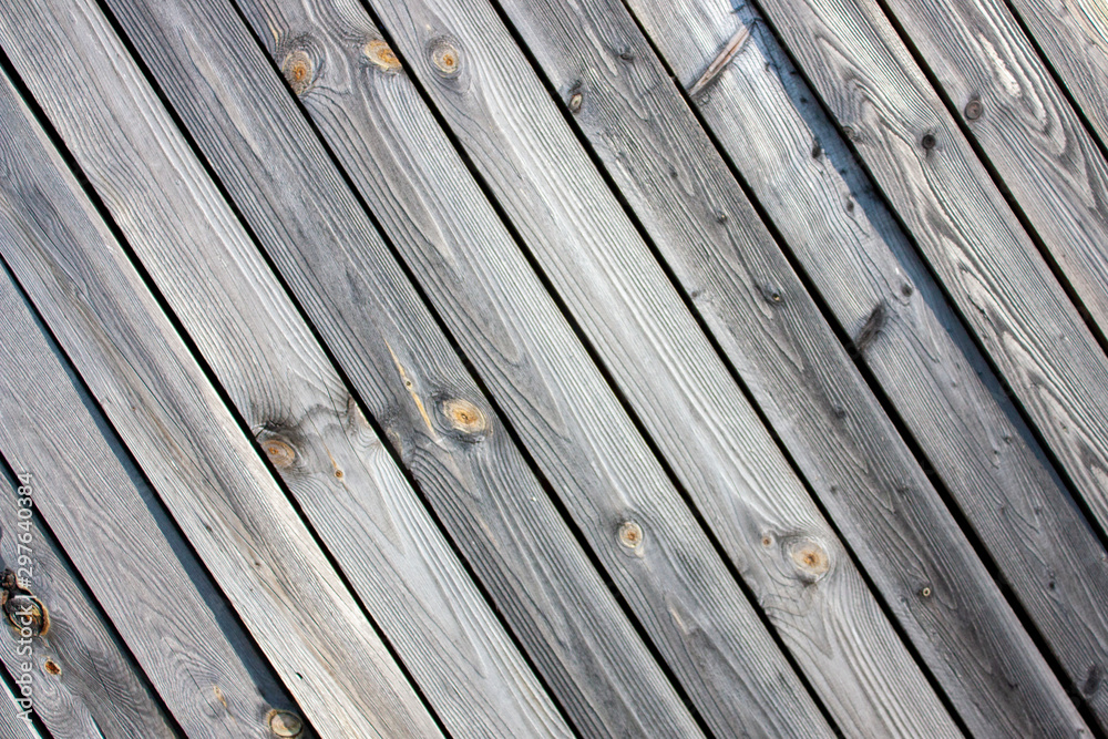 The wall of old boards natural wood. Weathered planks with a diagonal pattern. The tree darkened under the sun. The clear structure of the tree under the sun. The wall of old boards natural wood. Weathered planks with a diagonal pattern. The tree darkened under the sun. The clear structure of the tree under the sun.