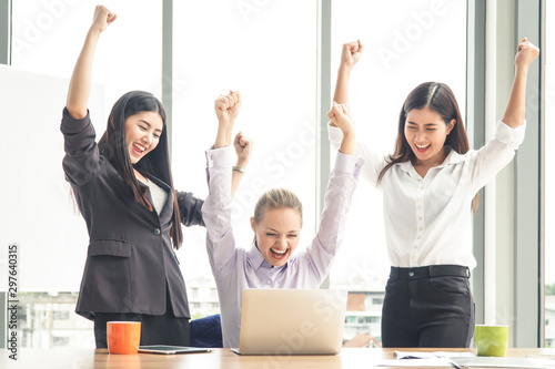 Three businesswomen putting their hands up and cheering with joy. Business and teamwork concept. © Pitchayaarch