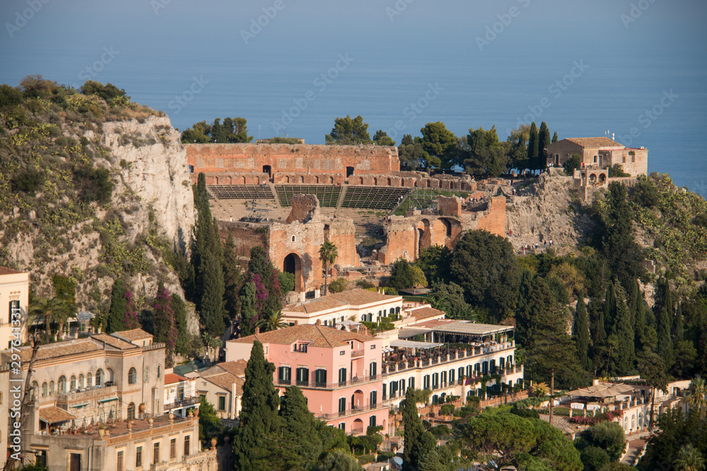 Beautiful panorama from mountain top to a small mediterranean sicilian town, Taormina, in warm sunset with the sea in the background, Sicily, Italy