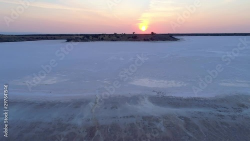 Forward drone flight low above shallow salt lake towards the sun at sunset in Australia photo