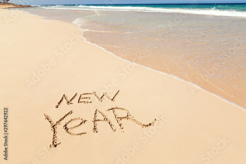 Inscription NEW YEAR on sandy beach