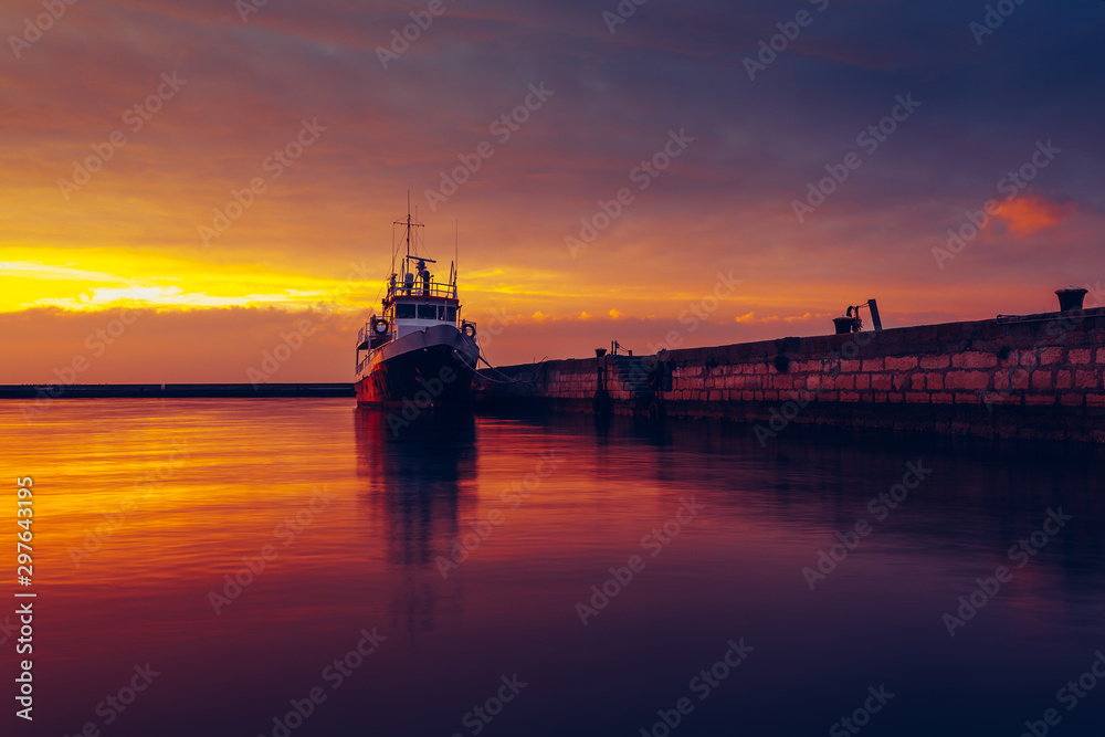 Harbor and boat under a colorful sunset.