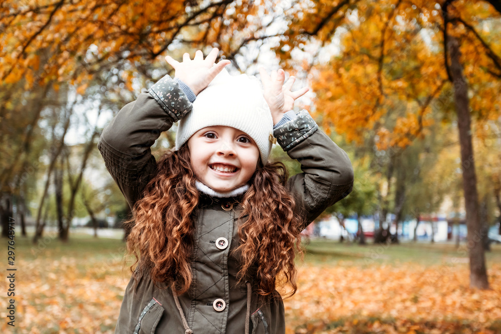 Autumn portrait of girl on nature in white hat. Little girl 5 years old having fun in autumn forest.
