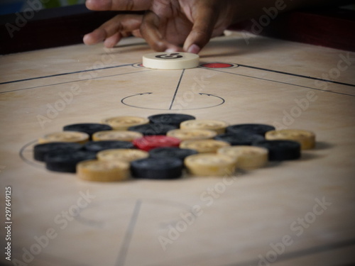 Side view of wooden carrom board game coins arranged by children for playing ready to strike
