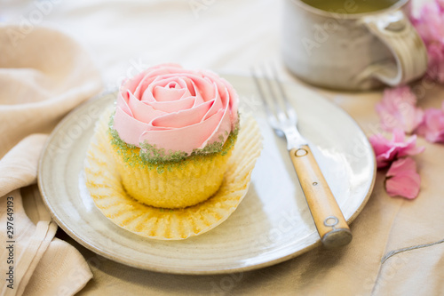 vanilla cupcake with pink frosting on plate