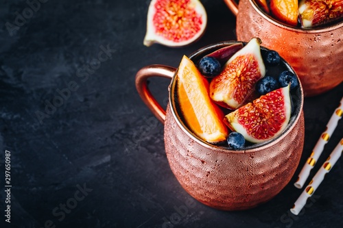 Fig moscow mule ice cold cocktail in copper cup with blueberries and orange