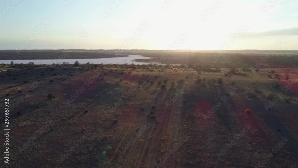 Slow aerial rise over desert revealing salt lake Kenyon facing the sun with lens flare in Australia Slow aerial rise over desert revealing salt lake Kenyon facing the sun with lens flare in Australia