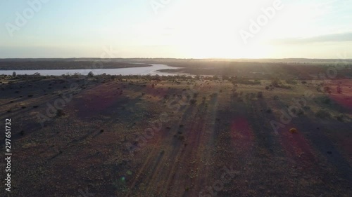 Slow aerial rise over desert revealing salt lake Kenyon facing the sun with lens flare in Australia photo