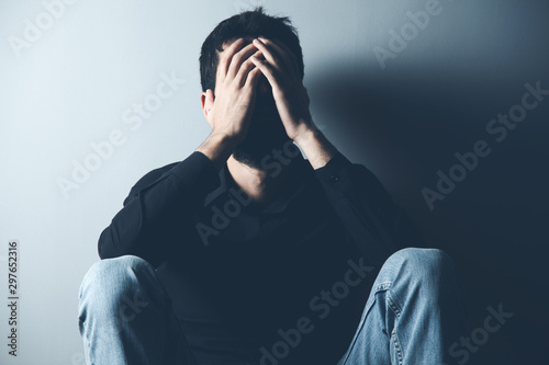 Fotografia sad man sitting on ground on dark background