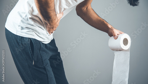 man holding a roll of toilet paper on gray background photo