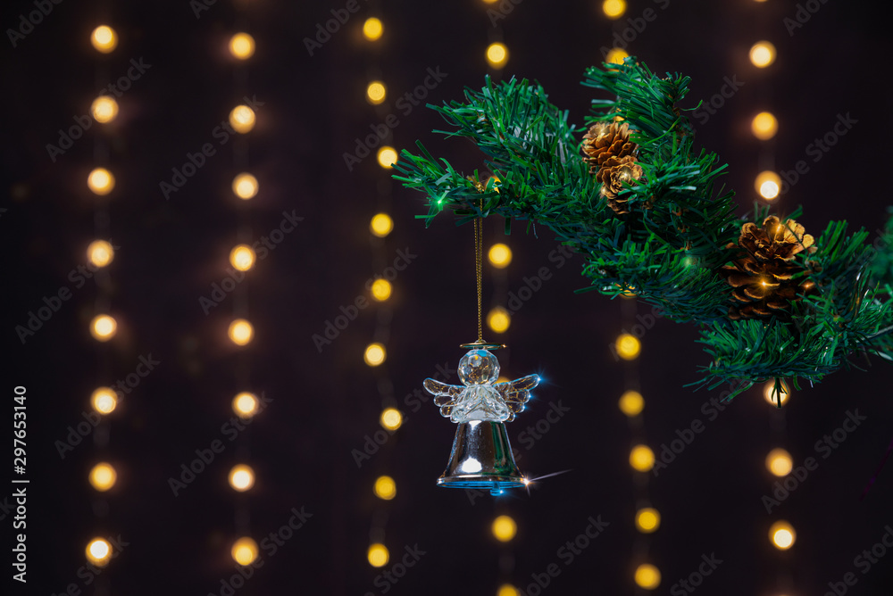 Obraz premium There is shiny silver angel on the green xmas tree branch with shiny cones. There are glowing lights/bokeh and on the background. Merry Christmas. Happy New Year 2020. 