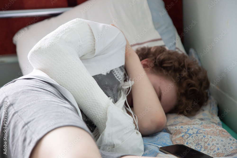 A patient with a broken arm is lying in hospital on a bed. A patient with a broken arm is lying in hospital on a bed.
