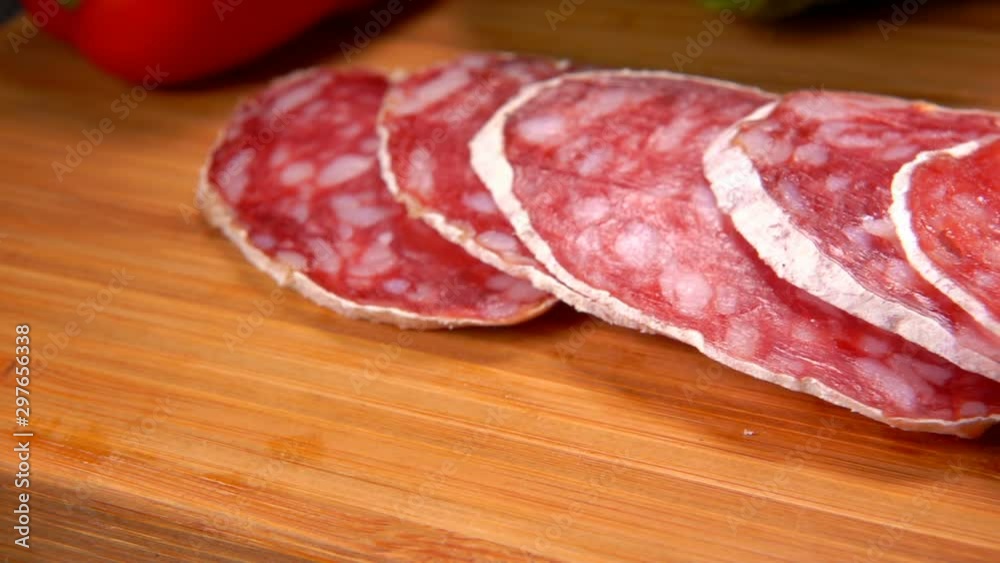 Delicious slices of dry sausage taken from wooden surface with a fork Delicious slices of dry sausage taken from wooden surface with a fork