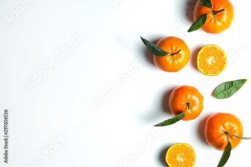 Close up image of juicy organic whole and halved oranges with green leaves & visible core texture, isolated white background, copy space. Macro shot of bright citrus fruit slices. Top view, flat lay.