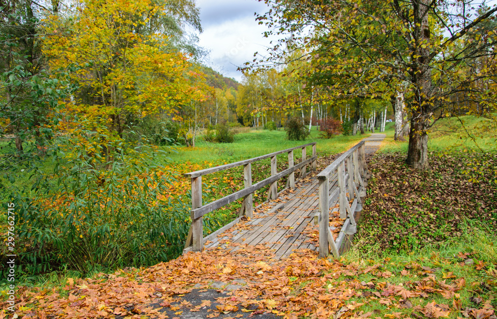 Wooden bridge over a stream. Yellow foliage and a bridge over a stream in autumn.