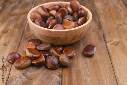 Cup of chestnuts on a wooden background. Autumn harvest and ripe fruits. Free space for text.