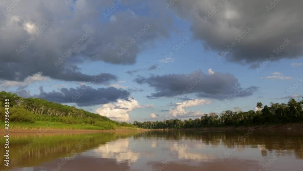 Beautiful view from a boat of Purus River at dusk in the Amazon on sunny summer day with trees on the river bank, blue sky and clouds in the background. Nature, conservation and environment concept. Beautiful view from a boat of Purus River at dusk in the Amazon on sunny summer day with trees on the river bank, blue sky and clouds in the background. Nature, conservation and environment concept.