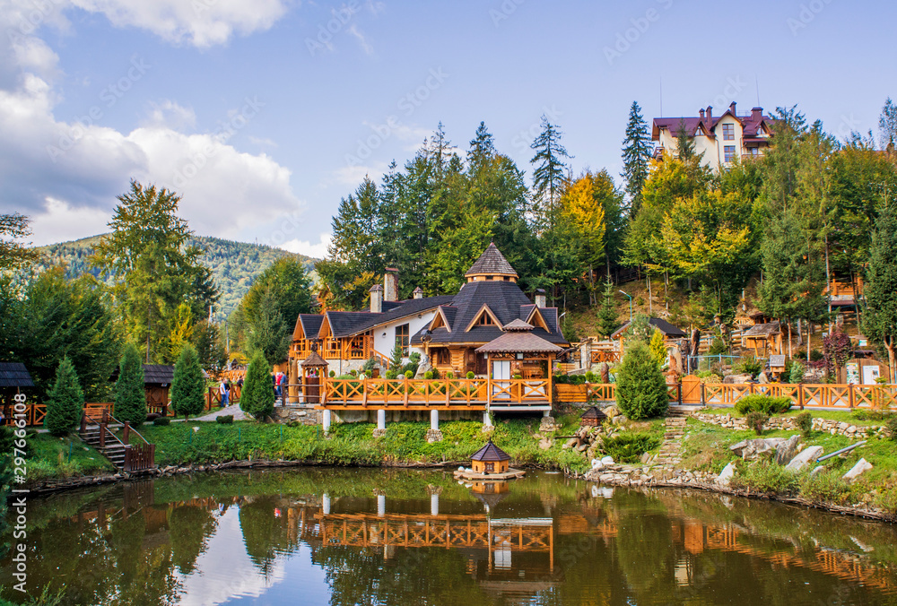 Jaremche/Ukraine - October 20 2019: Beautiful fairy tale yellow wood house. Park ensemble with a fence near the pond. Jaremche/Ukraine - October 20 2019: Beautiful fairy tale yellow wood house. Park ensemble with a fence near the pond.