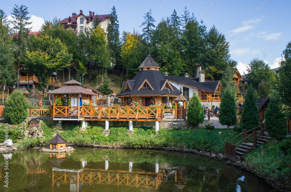 Jaremche/Ukraine - October 20 2019: Beautiful fairy tale yellow wood house. Park ensemble with a fence near the pond.