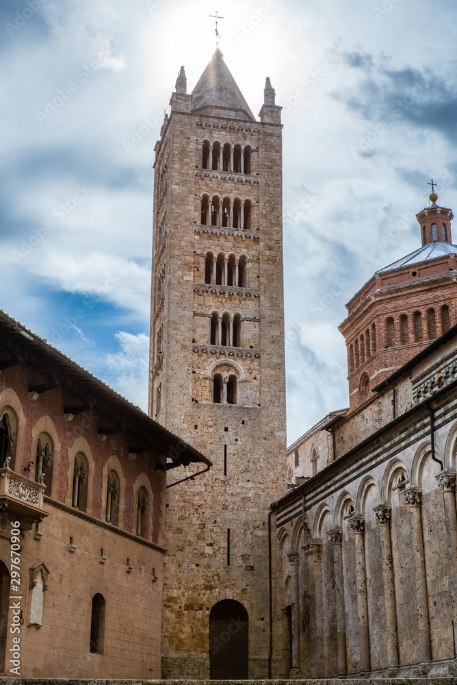 View of the bell tower of Massa Marittima in Tuscany with the sun in the background