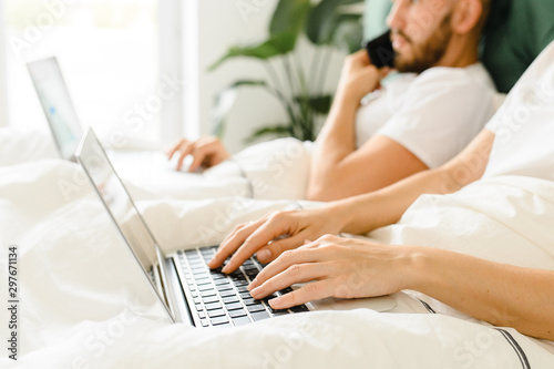 young couple uses laptop in bed. freelancer morning.