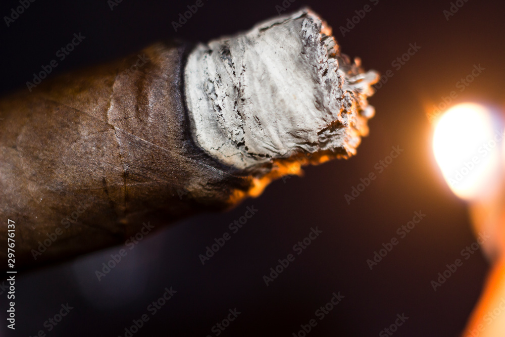 close up of a Cuban cigar being lit with a flame close up of a Cuban cigar being lit with a flame