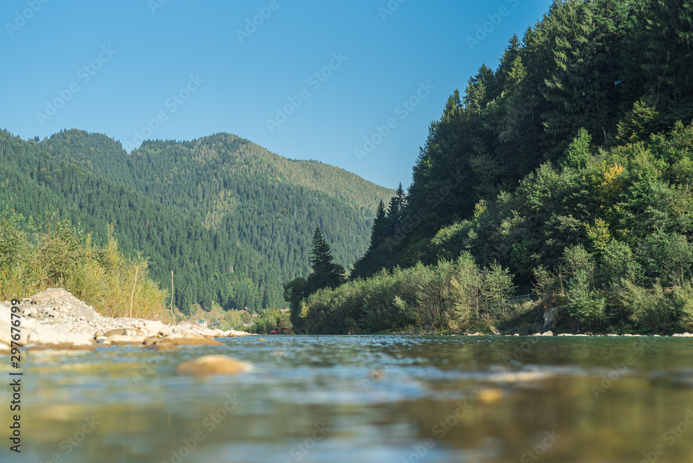 A river flows between mountains covered in forests.