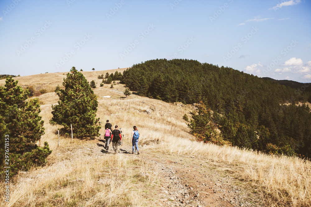 Rear view of unrecognizable people with backpack hiking in the nature